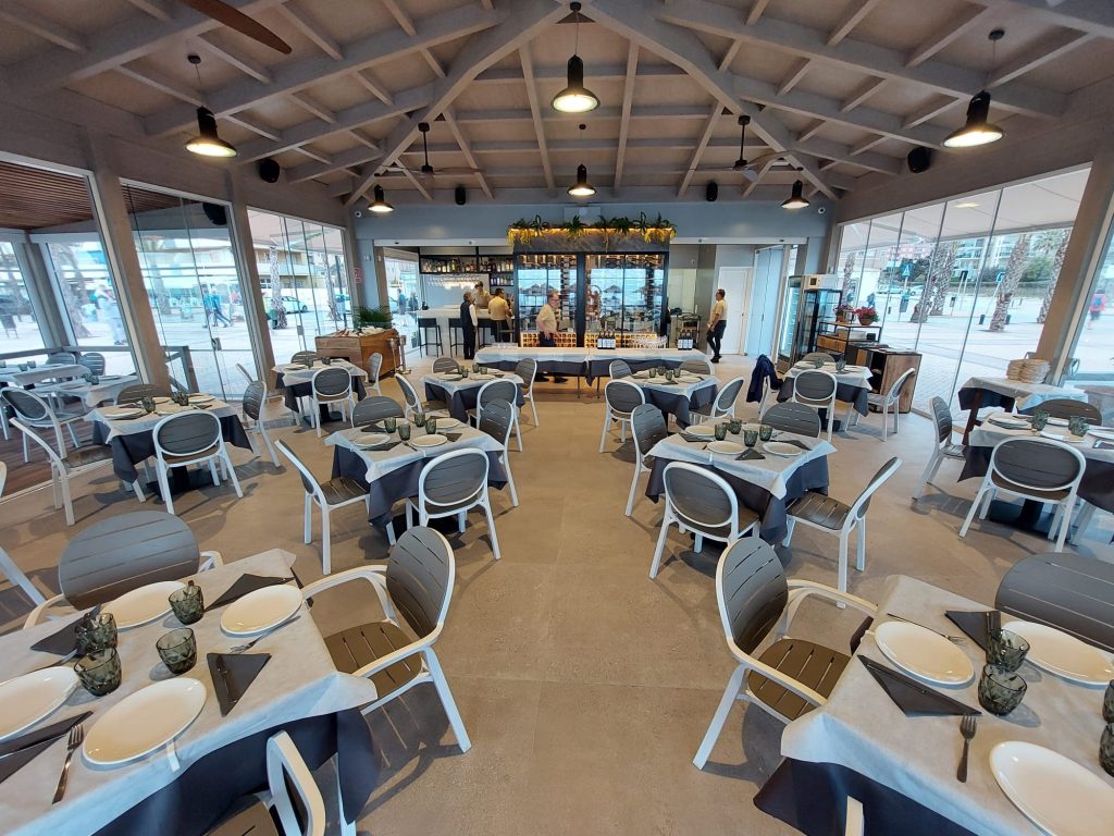 Interior del Restaurante Juan Playa, con las mesas, sillas y la barra de fondo.