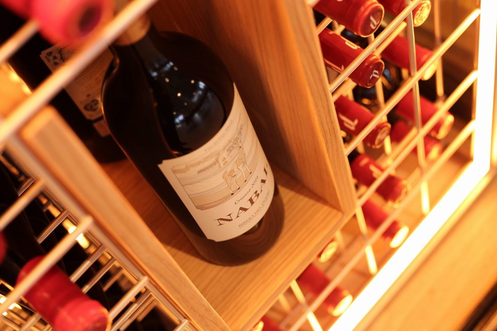 Botella de vino tinto en estantería de bodega